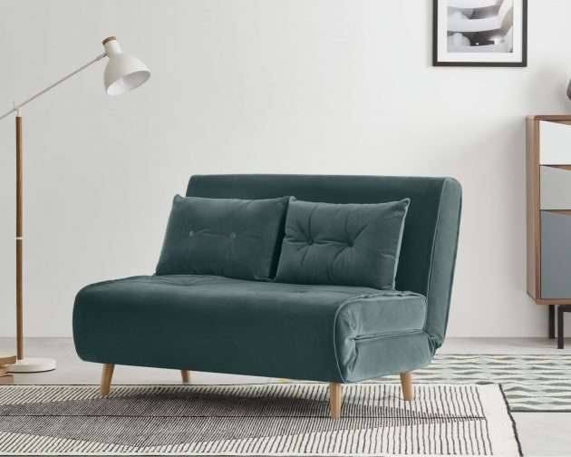 A small sofa bed upholstered in green velvet