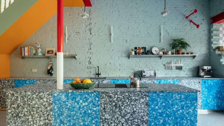 خزانات المطبخ اللافتة للنظر مصنوعة من أغطية زجاجات الحليب المعاد تدويرها ، المصنعة بواسطة Smile Plastics في ويلز. على الحائط سهام حمراء "تخترق" الجدار ، تمثال ليام فالون. عبر الغرفة ، يوجد مطعم ماكدونالدز M في الزاوية. "إنها أيقونة البوب ،" يقول مات.