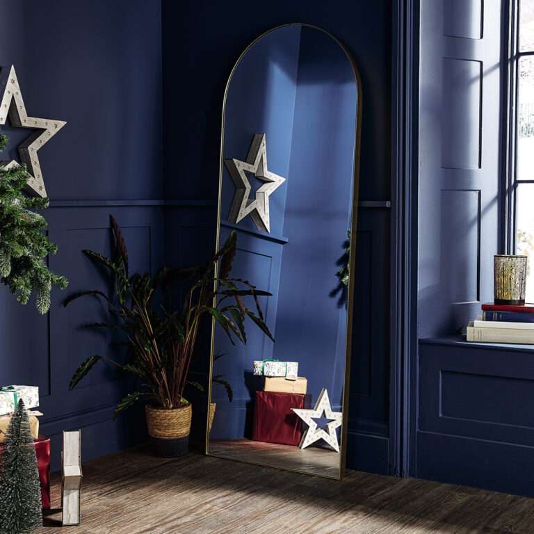 مرآة ذهبية قوسية من ألدي في غرفة الأعياد باللون الأزرق الداكن