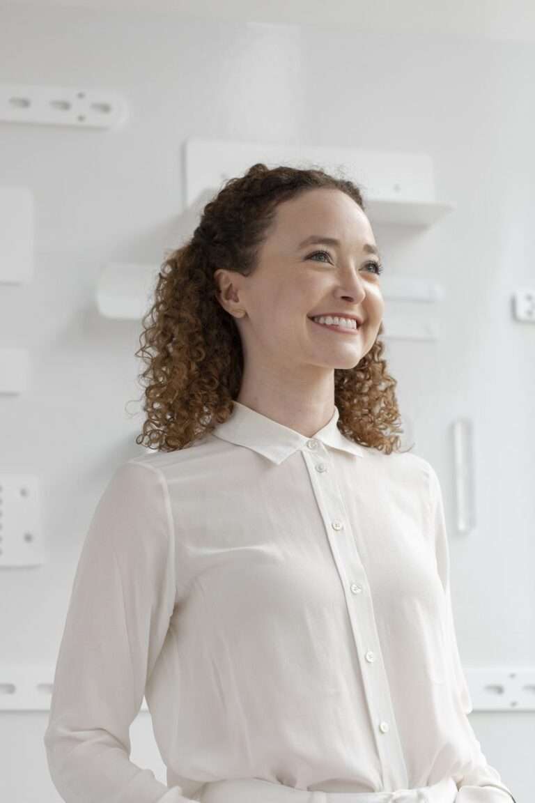 امرأة ذات بشرة فاتحة بشعر بني مجعد ترتدي قميصًا أبيض أسفل القميص