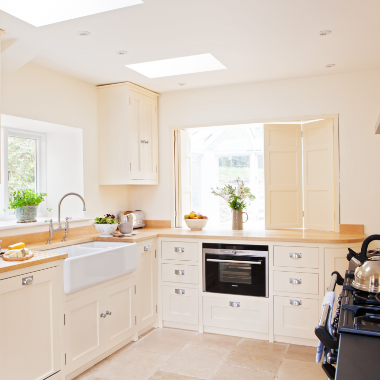 مطبخ كريم مع مغسلة وفرن وأضواء في السقف