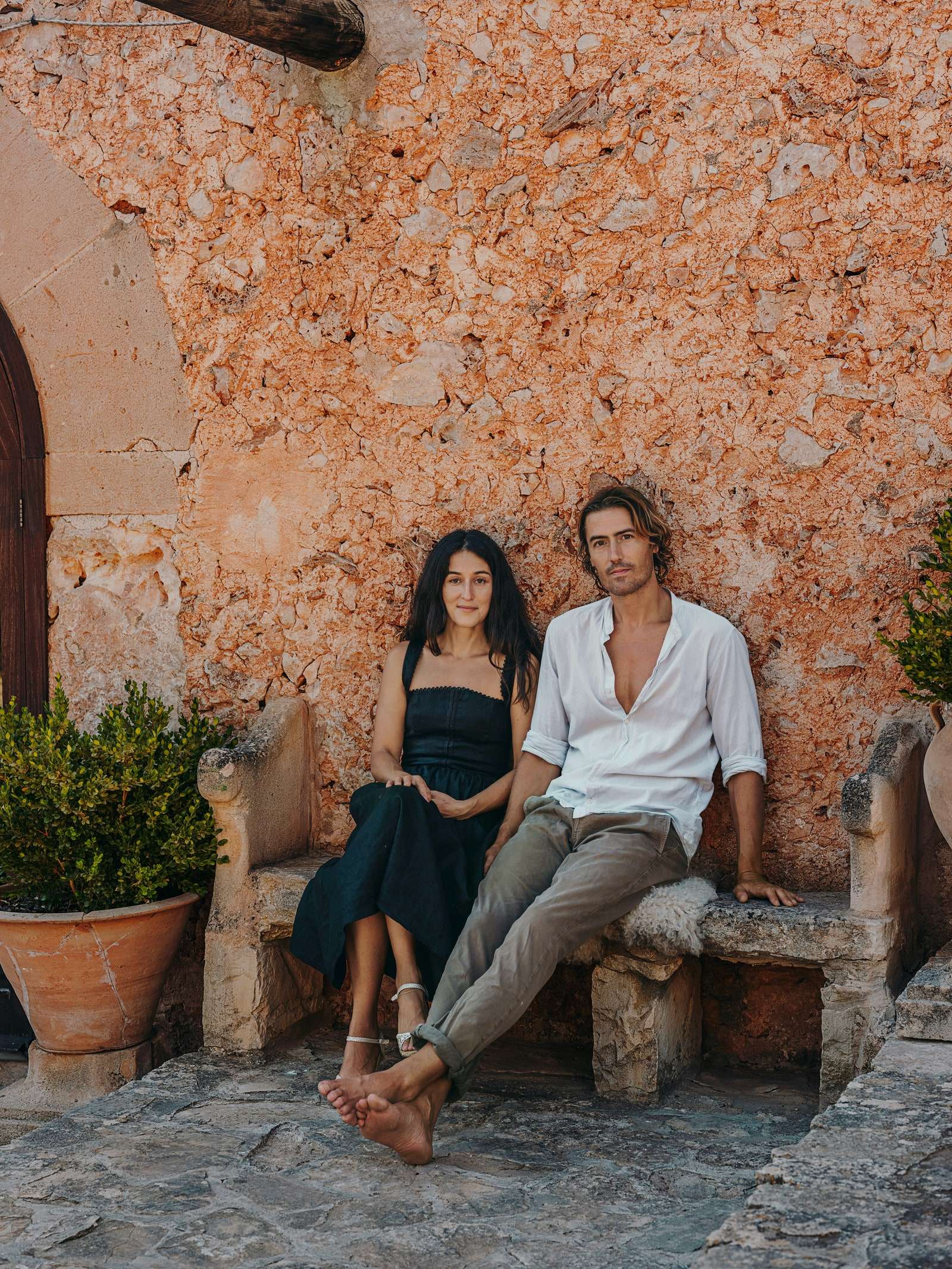 رجل وامرأة يجلسان على مقعد حجري خارج منزل