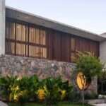 A Round Window Is Nestled Into A Stone Wall On The Front Of This Home
