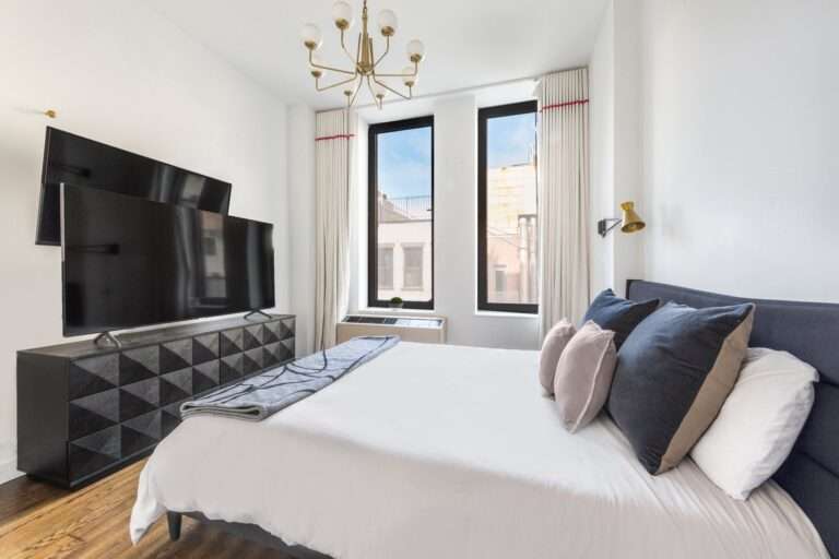 غرفة نوم مع تلفزيون سرير ونوافذ.