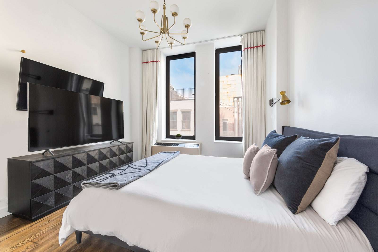 غرفة نوم مع تلفزيون سرير ونوافذ.