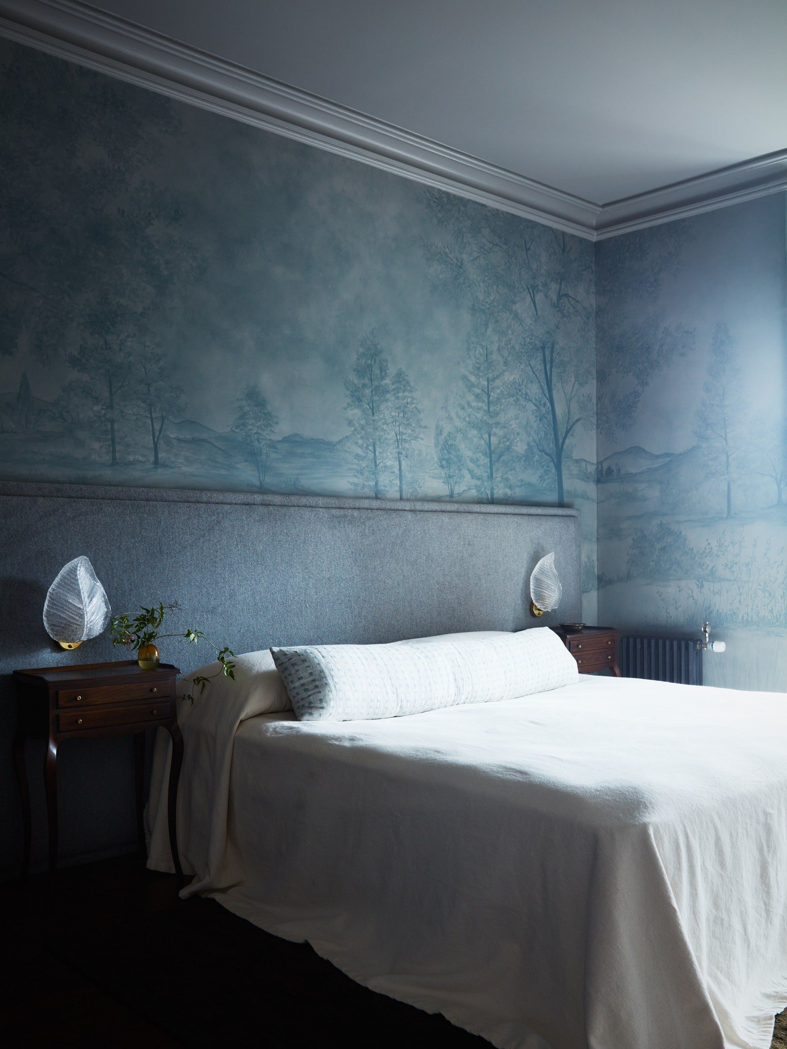 In a clients Booklyn Heights bedroom designer Augusta Hoffman pairs a scenic wall covering with an ivory bedcover.