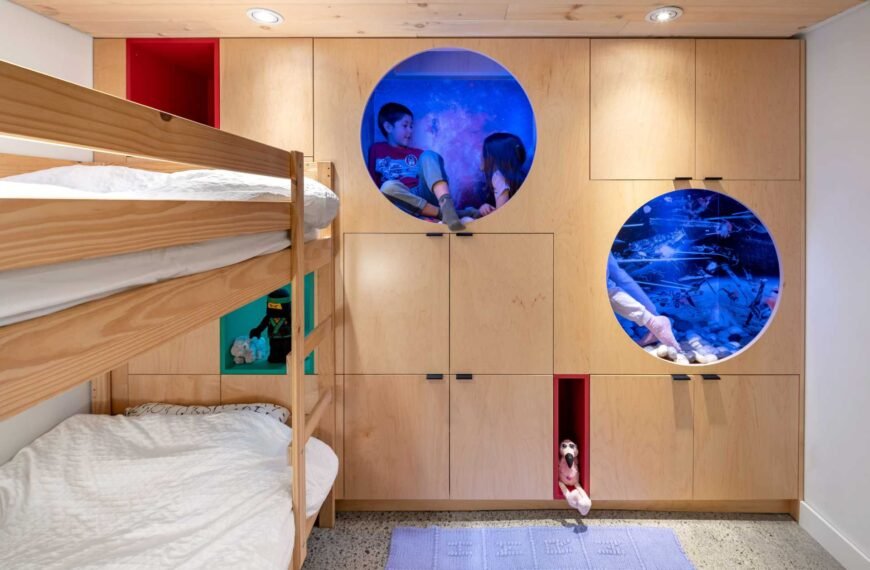 A kids bedroom with built-in storage in the form of cabinets and benches, as well as bunk beds, and two reading nooks.