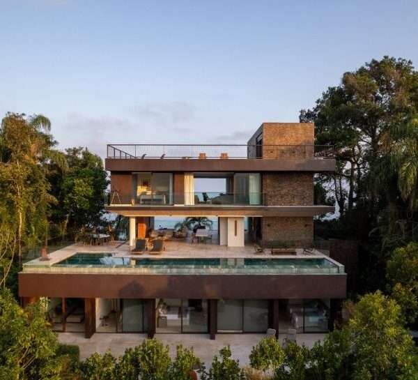 FCstudio's coastal house stacks steel, glass, & stone layers amid são paulo's rugged terrain