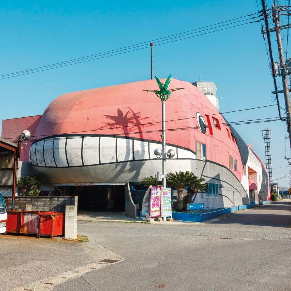 the facade of a love hotel in Japan along the roadside shaped like a giant pink whale