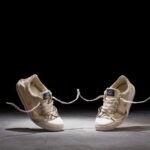 a still from a stop-motion animated short of two canvas sneakers dancing against a black background