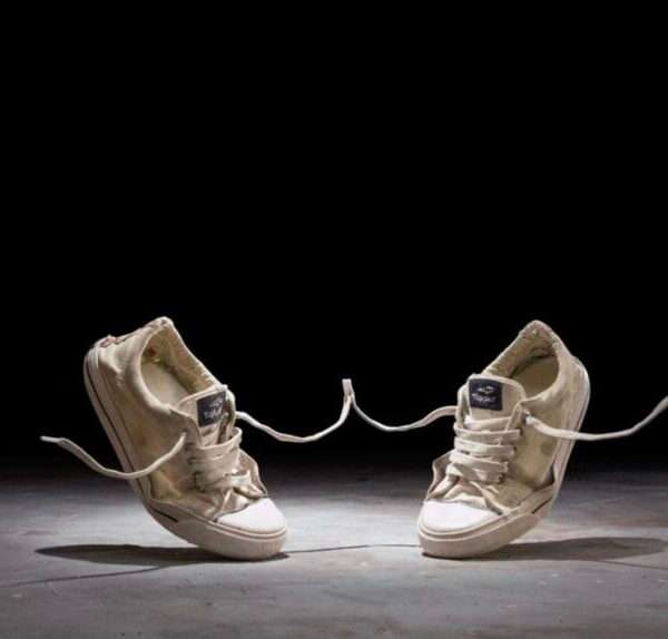 a still from a stop-motion animated short of two canvas sneakers dancing against a black background