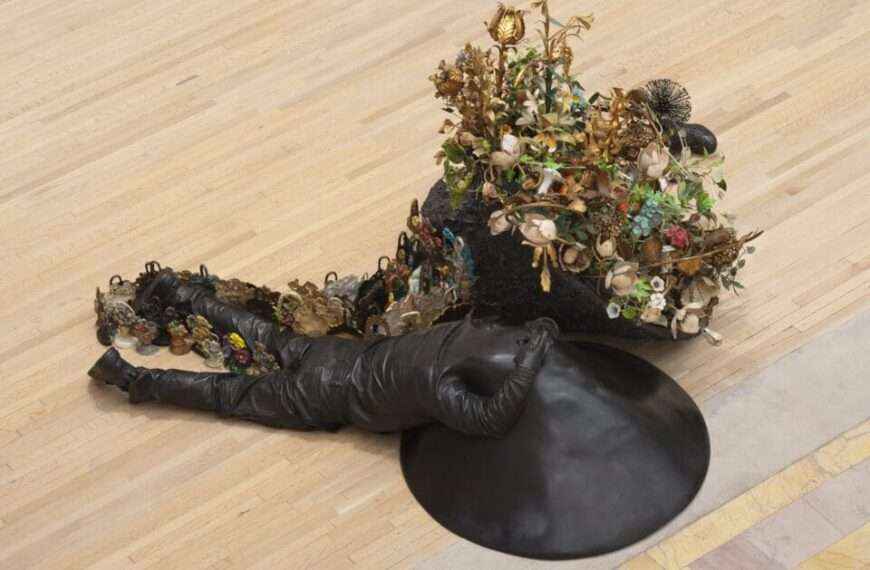 two bronze figures lay on the floor with flowers growing from them