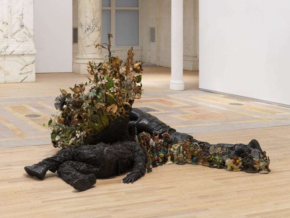 two bronze figures lay on the floor with flowers growing from them