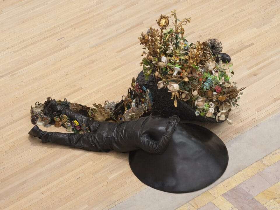 two bronze figures lay on the floor with flowers growing from them