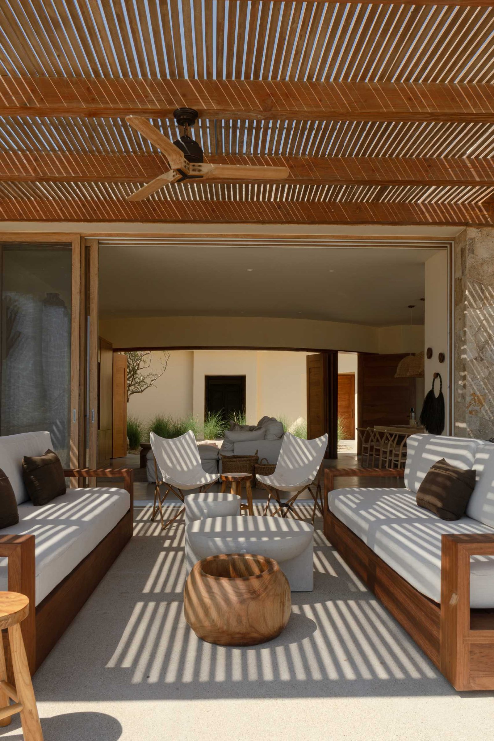 A contemporary stone home includes a spacious terrace, as well as a series of sculptural concrete cubes that form the pool and jacuzzi, while steps lead directly to the sand.