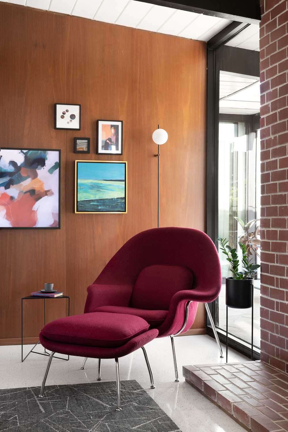 In the living room, the wood wall is accented by artwork, while a pop of colour has with furniture choices.