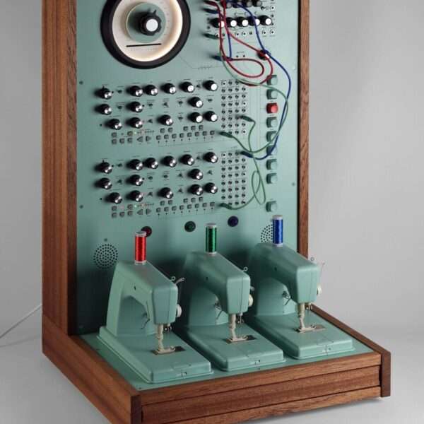 a sculpture resembling a retro computer or device in a teal hue with wood on the sides, with dials and wires and a row of three sewing machines on the base