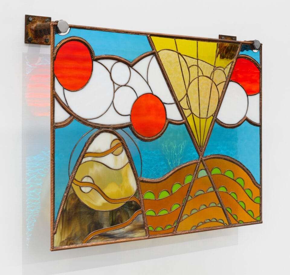 a stained glass wall installation depicting an abstract landscape with mountains and clouds