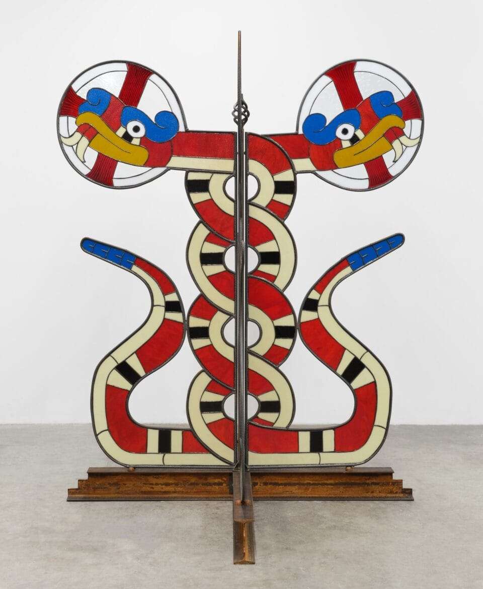a freestanding sculpture of two intertwined red-and-yellow snakes