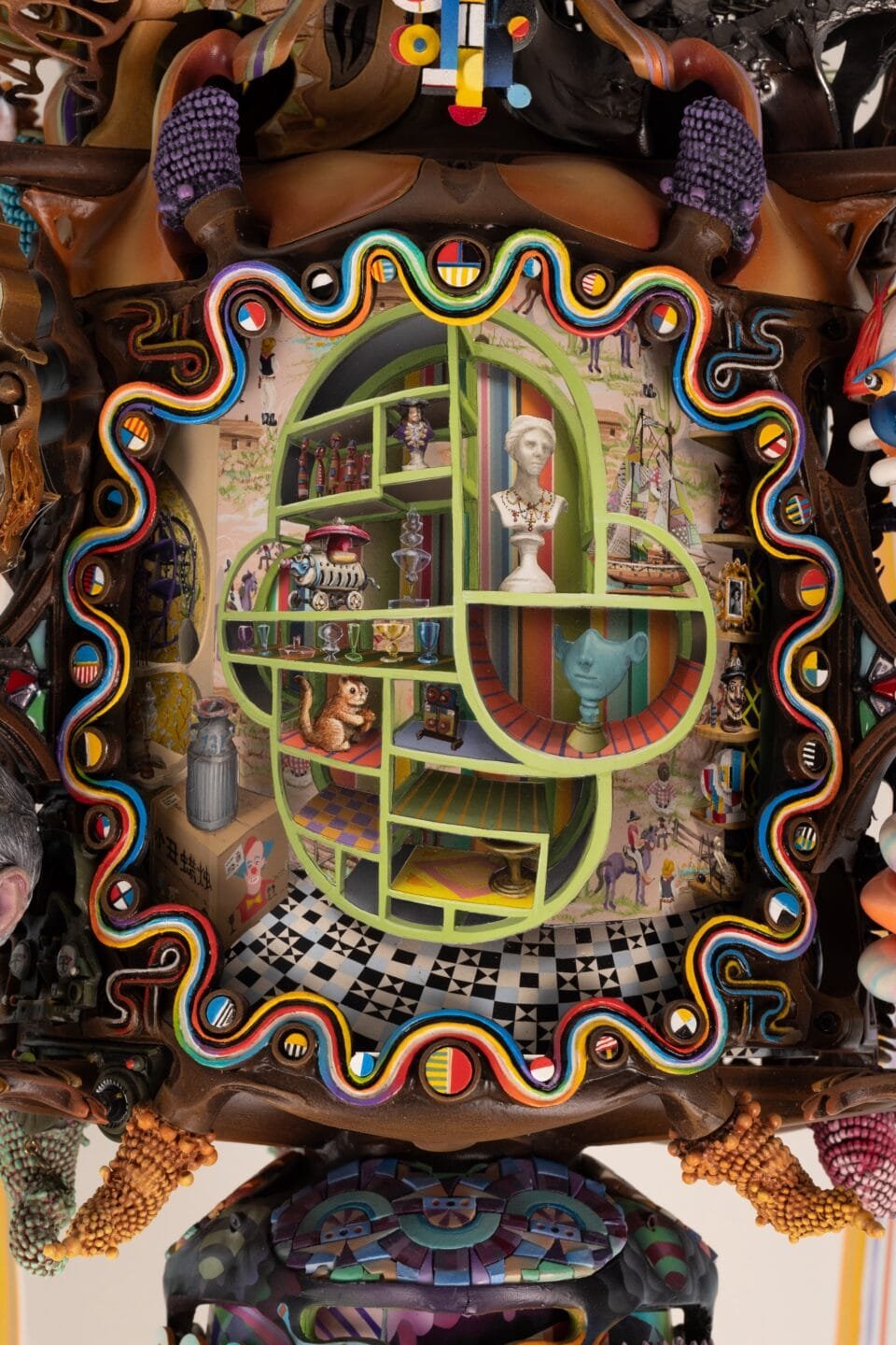 a close-up detail of part of an elaborately decorated sculpture with numerous sculpted, found, and painted elements, emphasizing a green painted detail with numerous compartments with tiny objects inside them