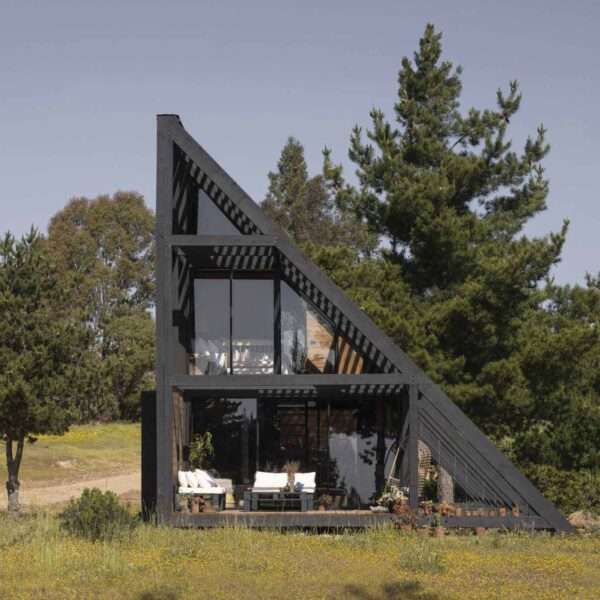 A small wedge-shaped home with a black exterior that's located on the windy beach of Matanzas, Chile.