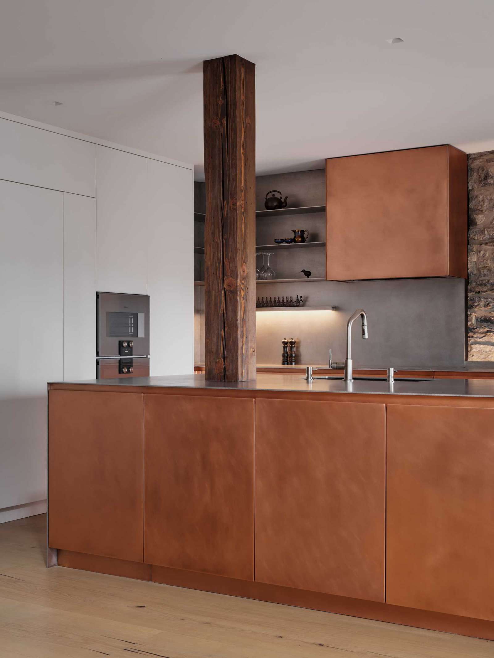 This modern kitchen in a renovated historic loft, features striking copper cabinetry and a stainless steel countertop.