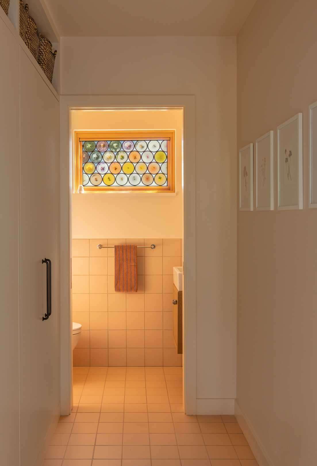 Custom stained glass windows cast playful shadows and pops of color to the updated powder room.