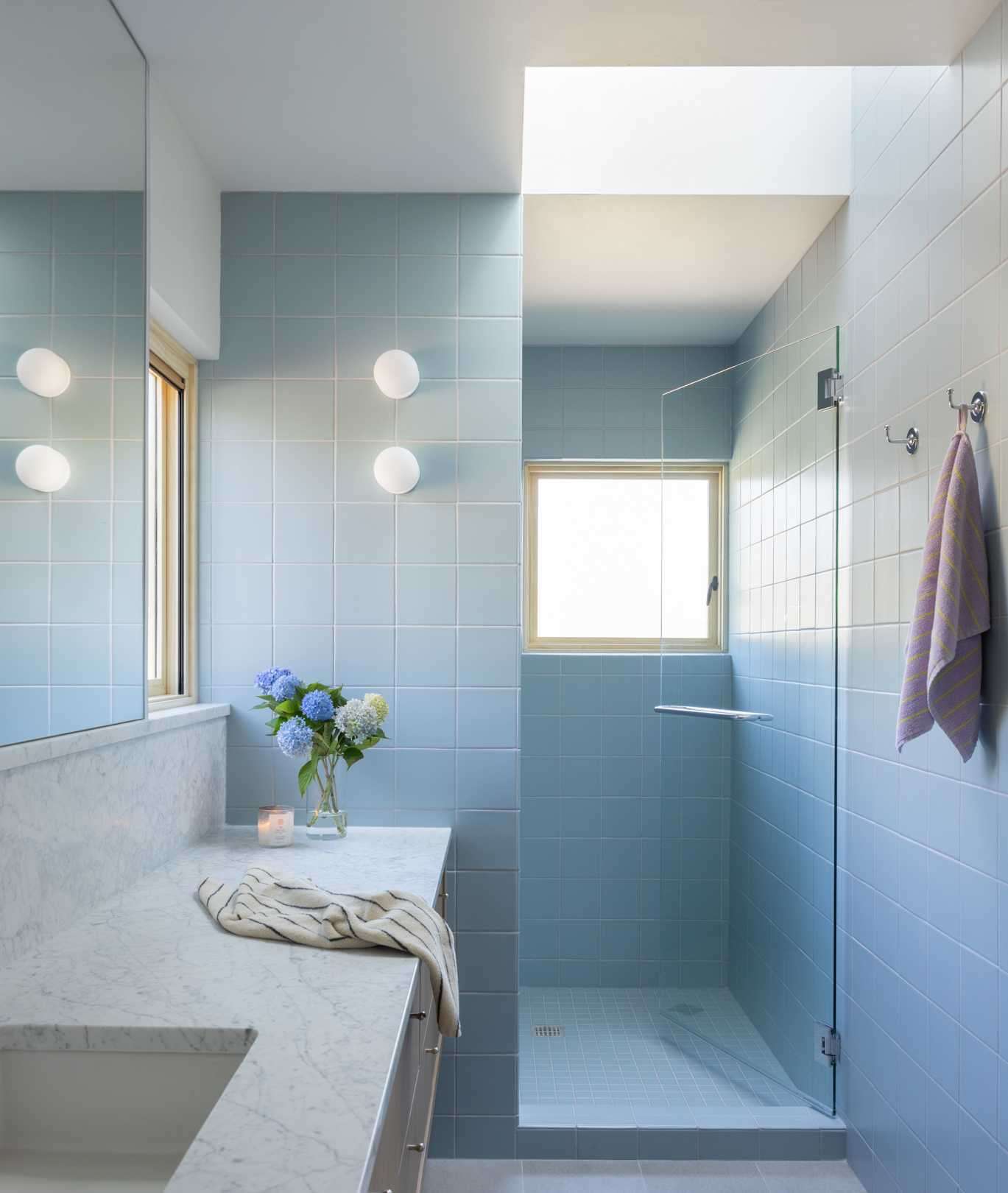 A spa-inspired blue tiled bathroom, white oak cabinetry in an open closet, and a convenient adjoining laundry area.