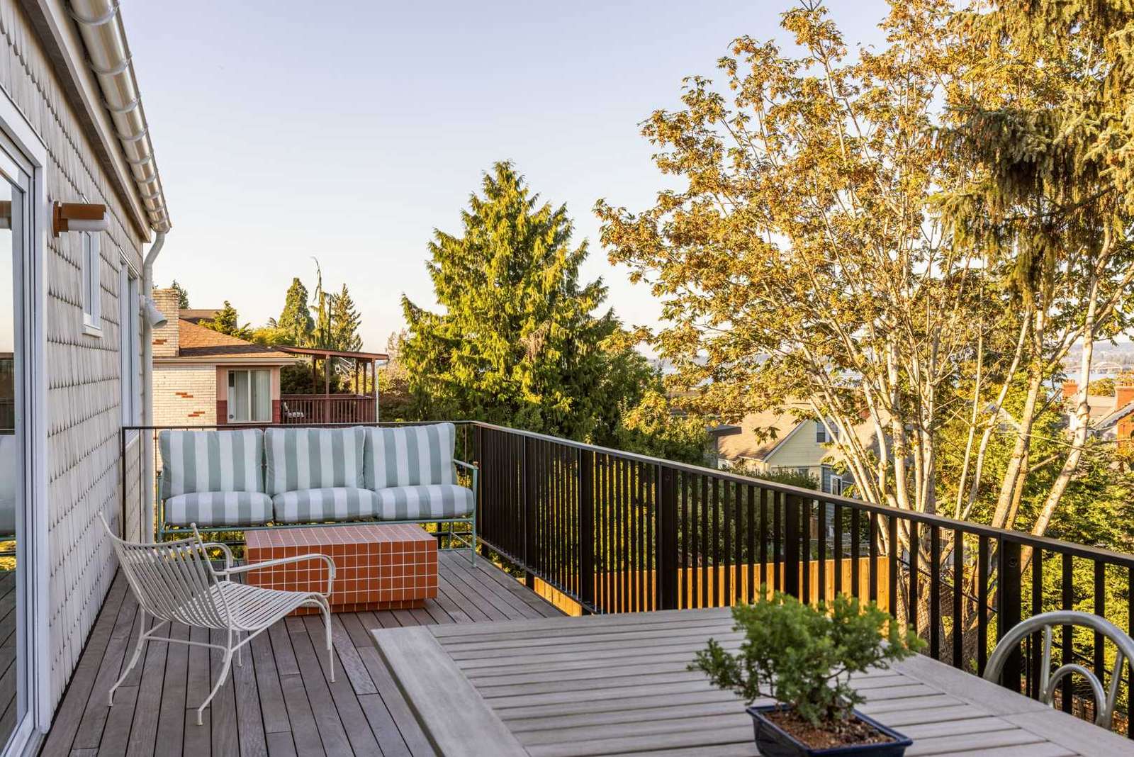 Elegant landscaping features carefully positioned stone patios encircled with native plants and trees, fenced areas for privacy, and stepping stones to the backyard, while the deck has stairs connecting to the garden.