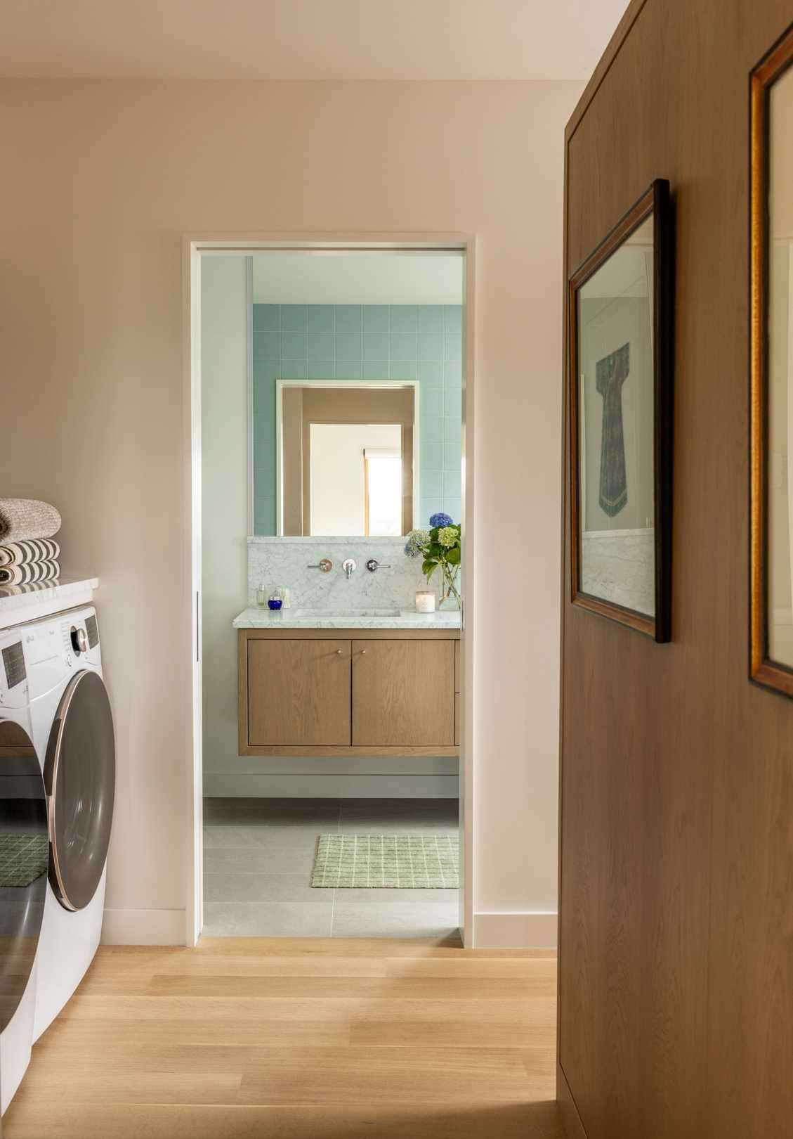 A spa-inspired blue tiled bathroom, white oak cabinetry in an open closet, and a convenient adjoining laundry area.