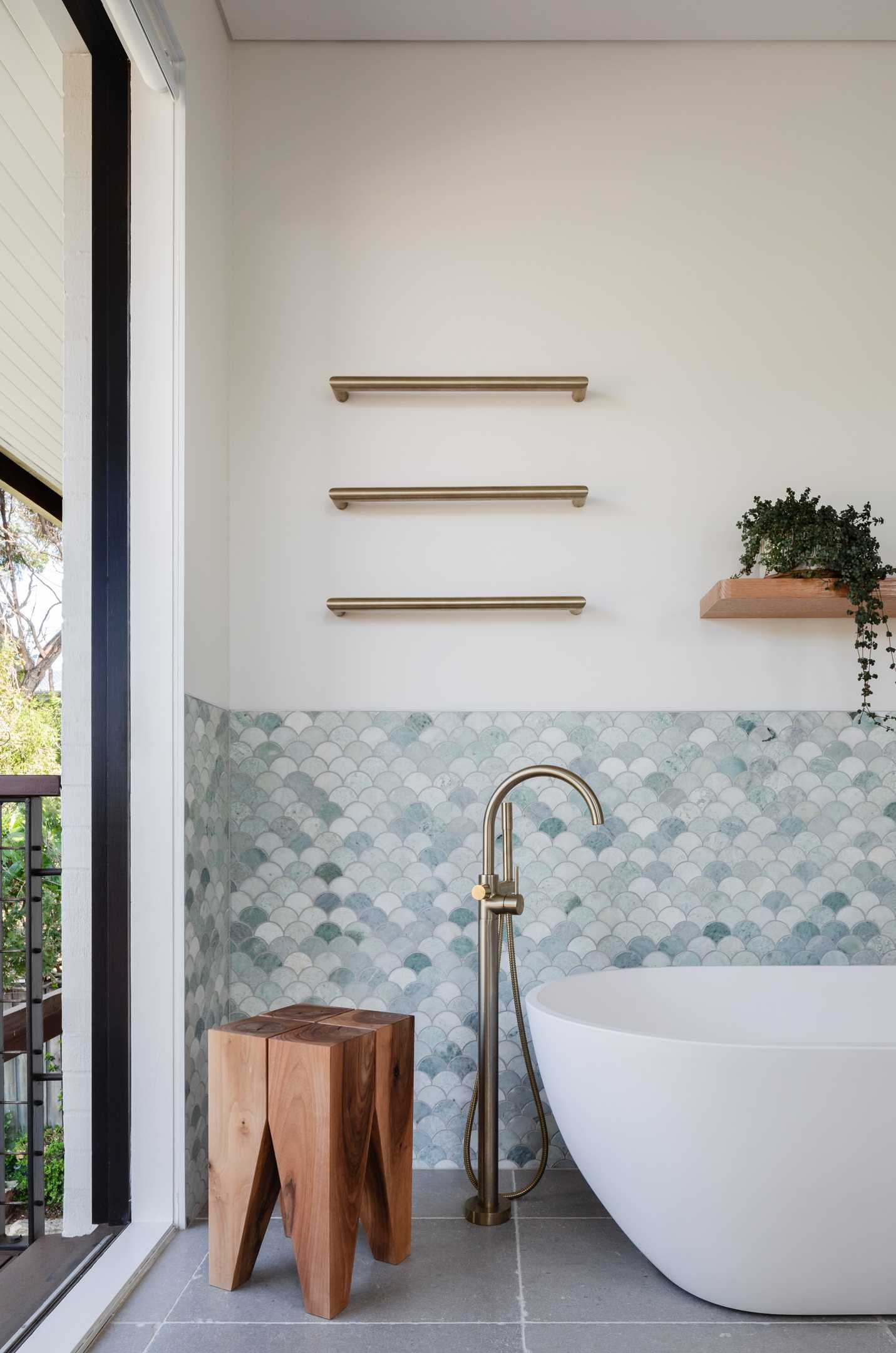 In this modern bathroom, Ming green marble fan tiles are featured on the walls, while the wood vanity and white and bronze accents complement the other updated areas in the home.
