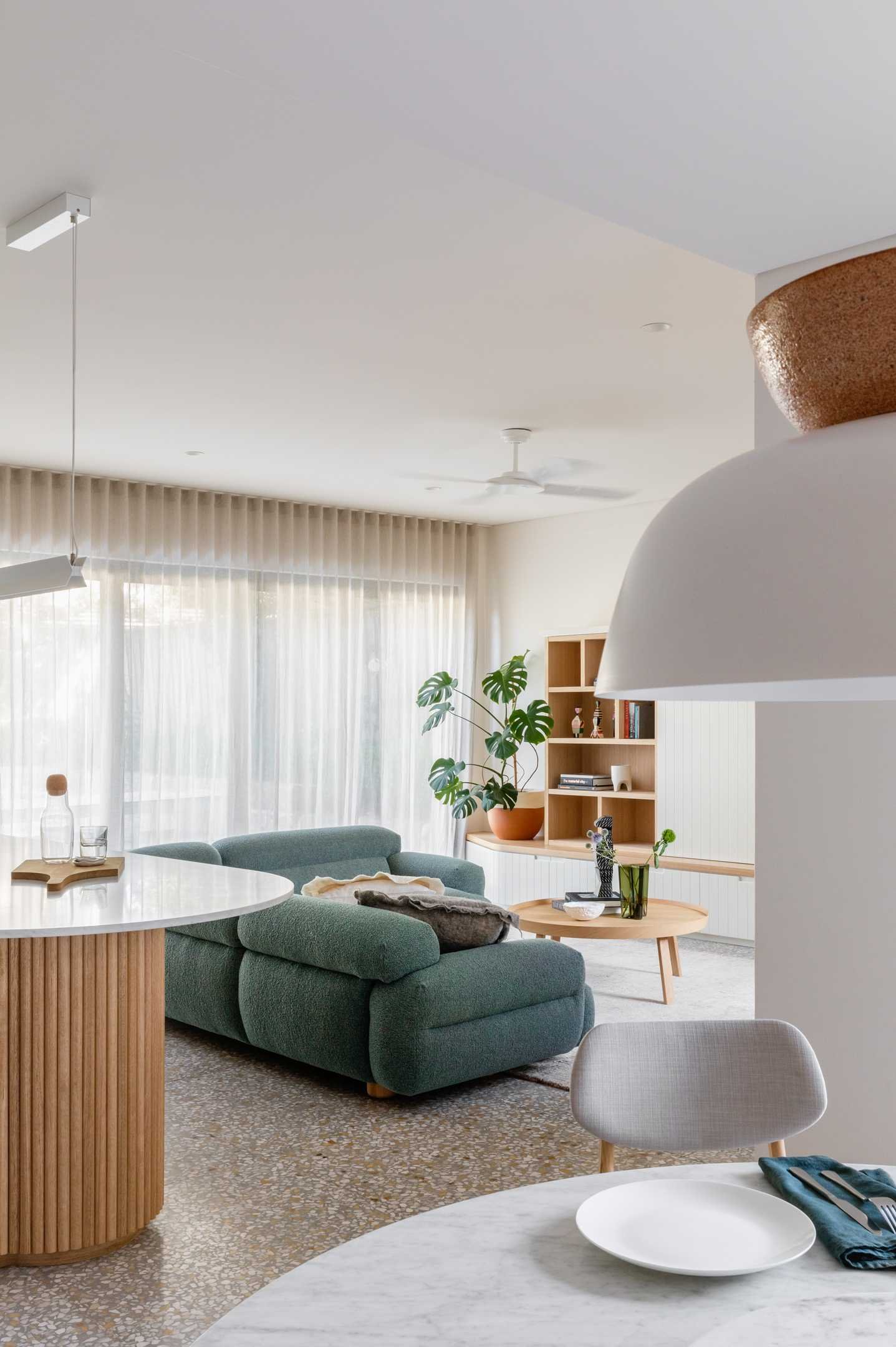 This modern living room has a wrap around wood shelving unit that doubles as a bench, and includes a custom cabinetry solution for additional storage.
