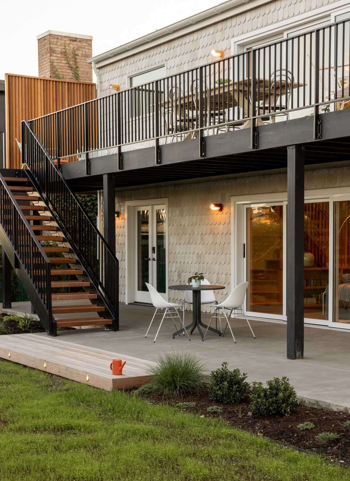 Elegant landscaping features carefully positioned stone patios encircled with native plants and trees, fenced areas for privacy, and stepping stones to the backyard, while the deck has stairs connecting to the garden.
