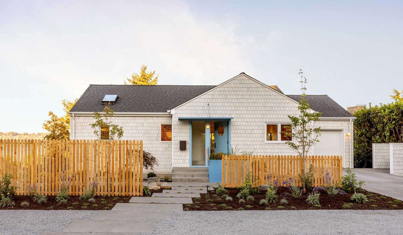 A renovated home with scalloped shingles and blue accents.