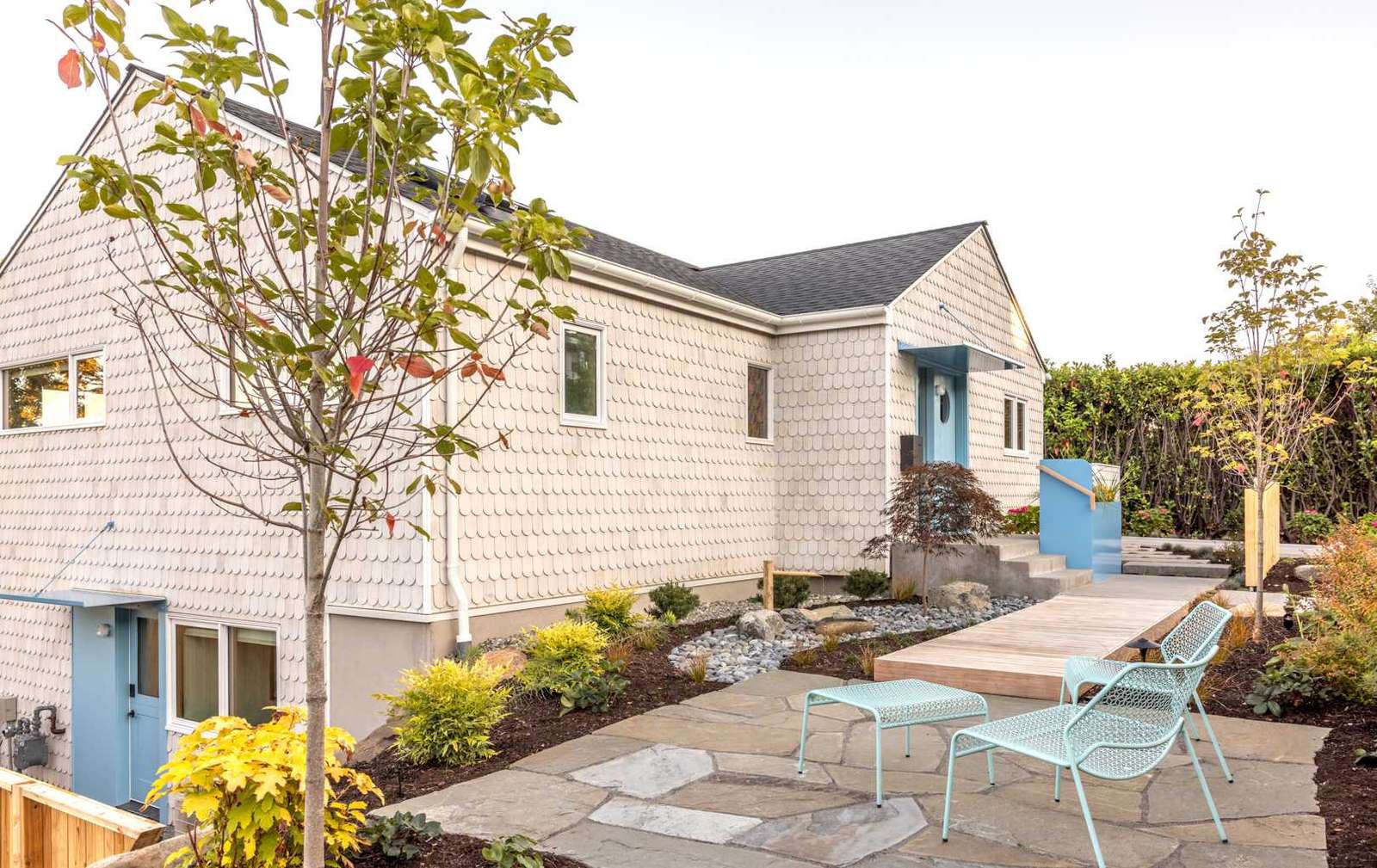 A renovated home with scalloped shingles and blue accents.