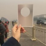 a white hand holding up a postcard to the sky