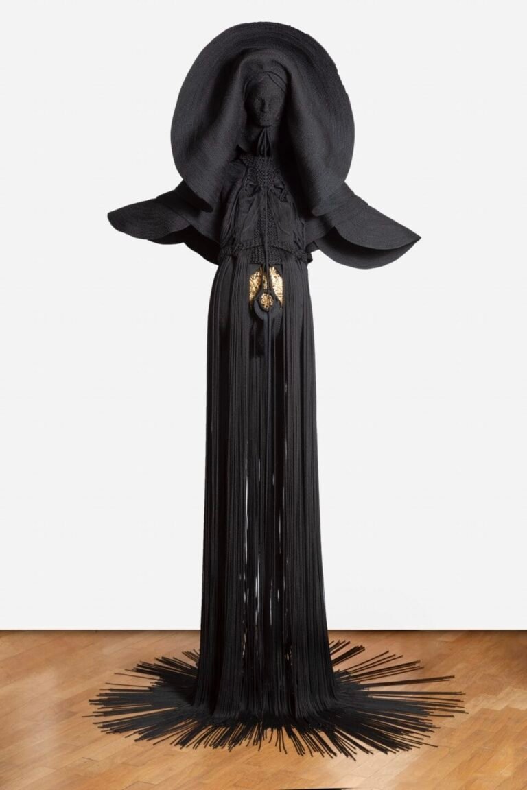 a sculpture made from black cord, thread, and metal in the form of a figure or long, dramatic garment