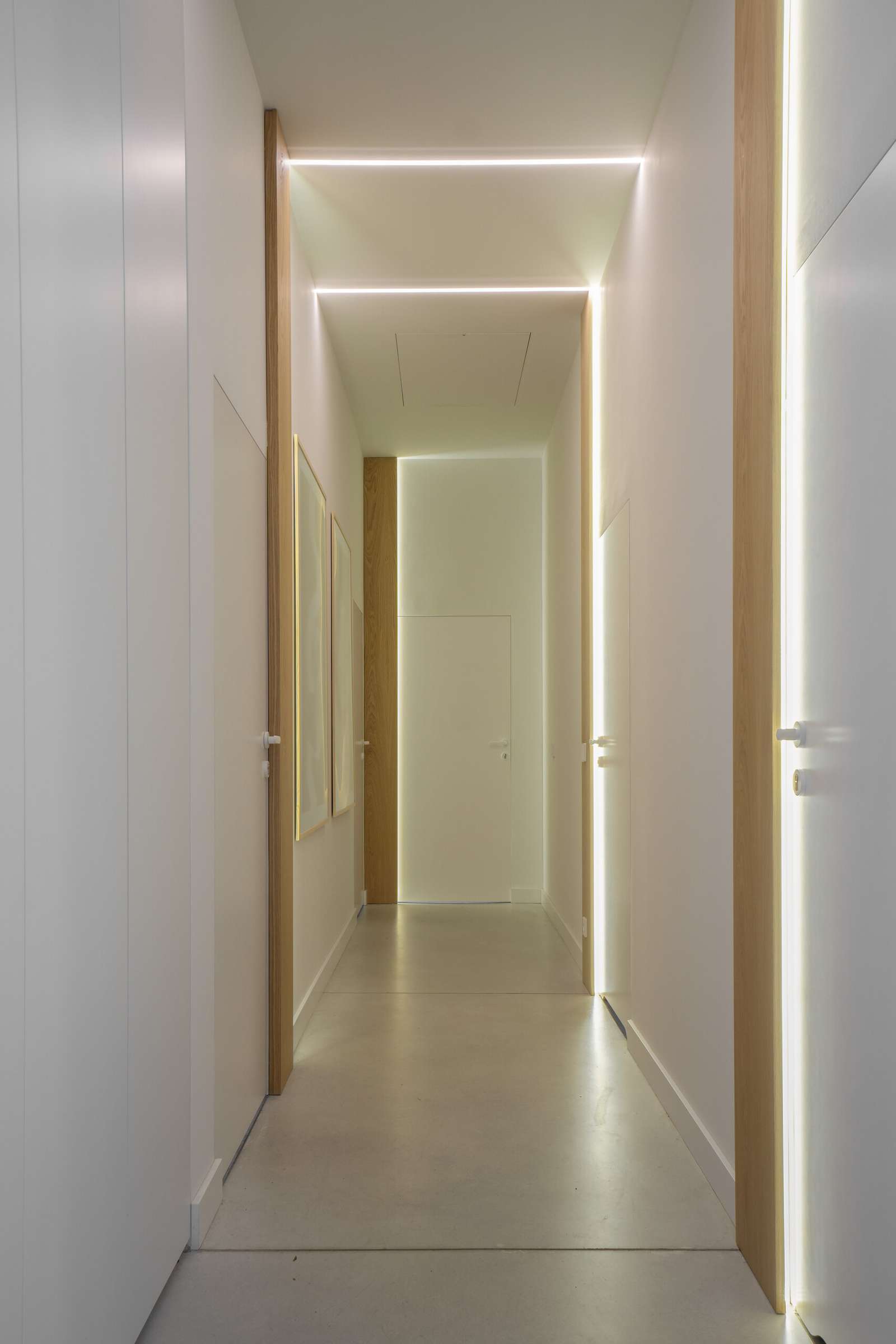 A hallway with integrated lighting leads from the social areas to the bedrooms and bathrooms.