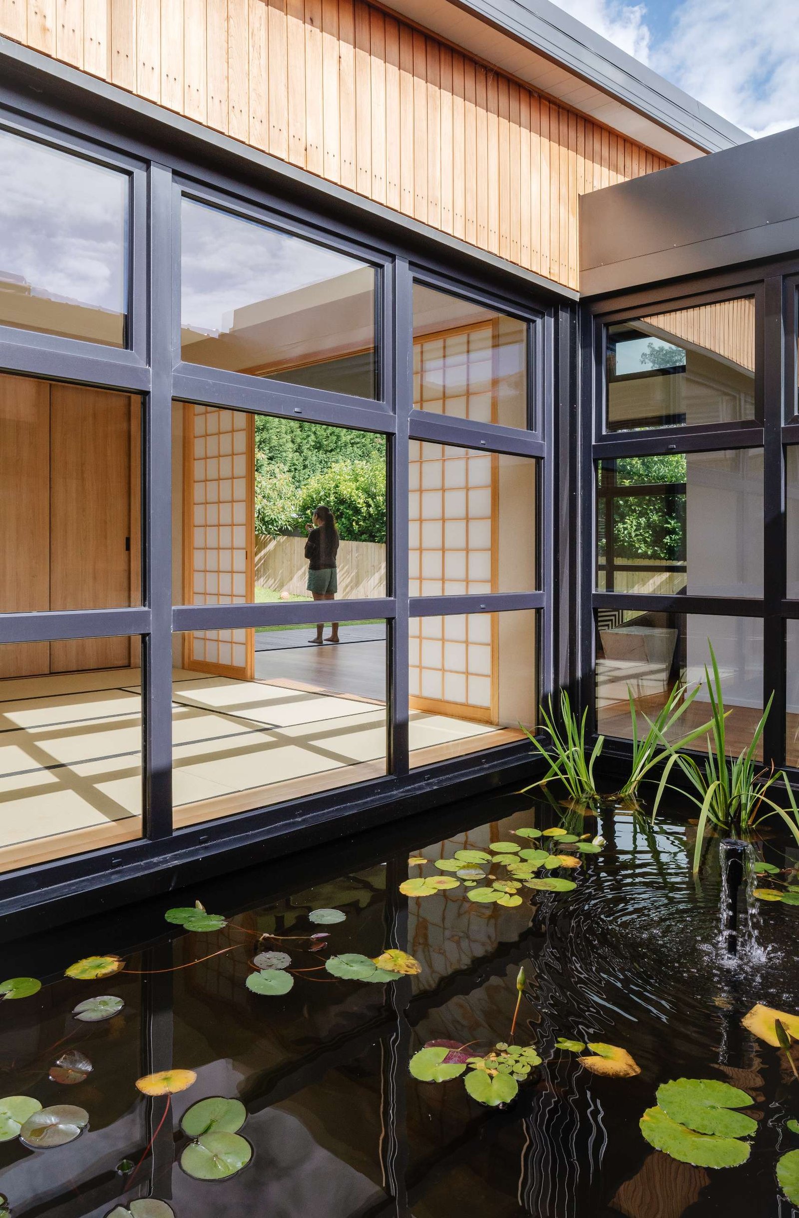 A tranquil courtyard reflection pond forms the serene heart of this home, framed by  black steel windows that invite nature into every room.