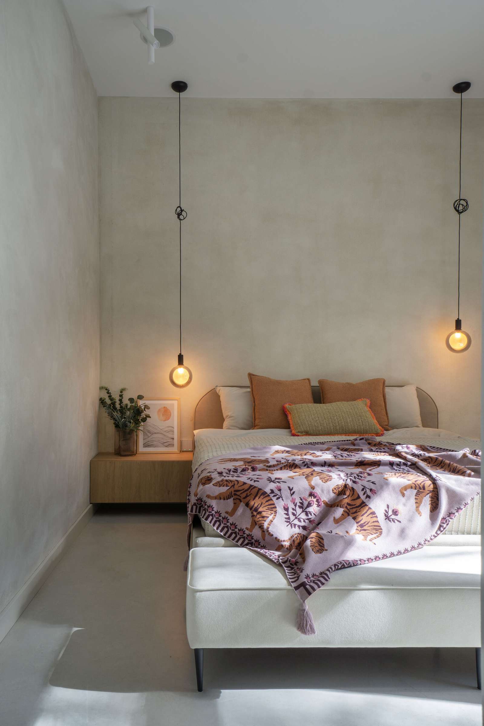 A modern bedroom with pendant lights acting as bedside lamps.