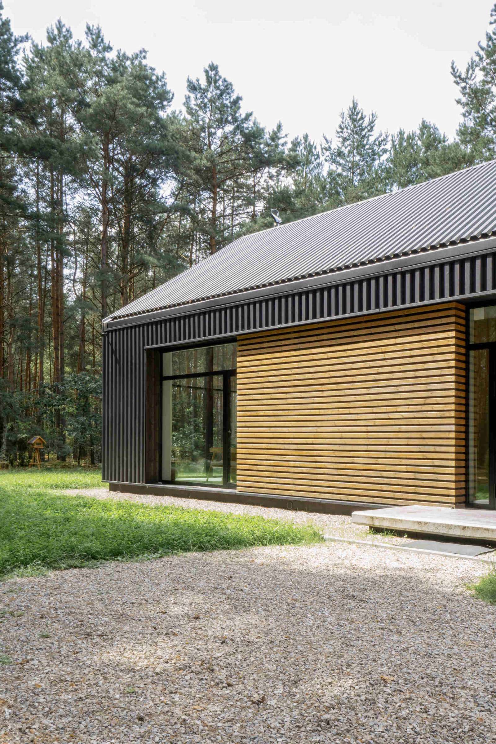 The facade of this modern home is clad in black metal, creating a striking and contemporary appearance, while wood accents add warmth and a natural touch to the exterior.