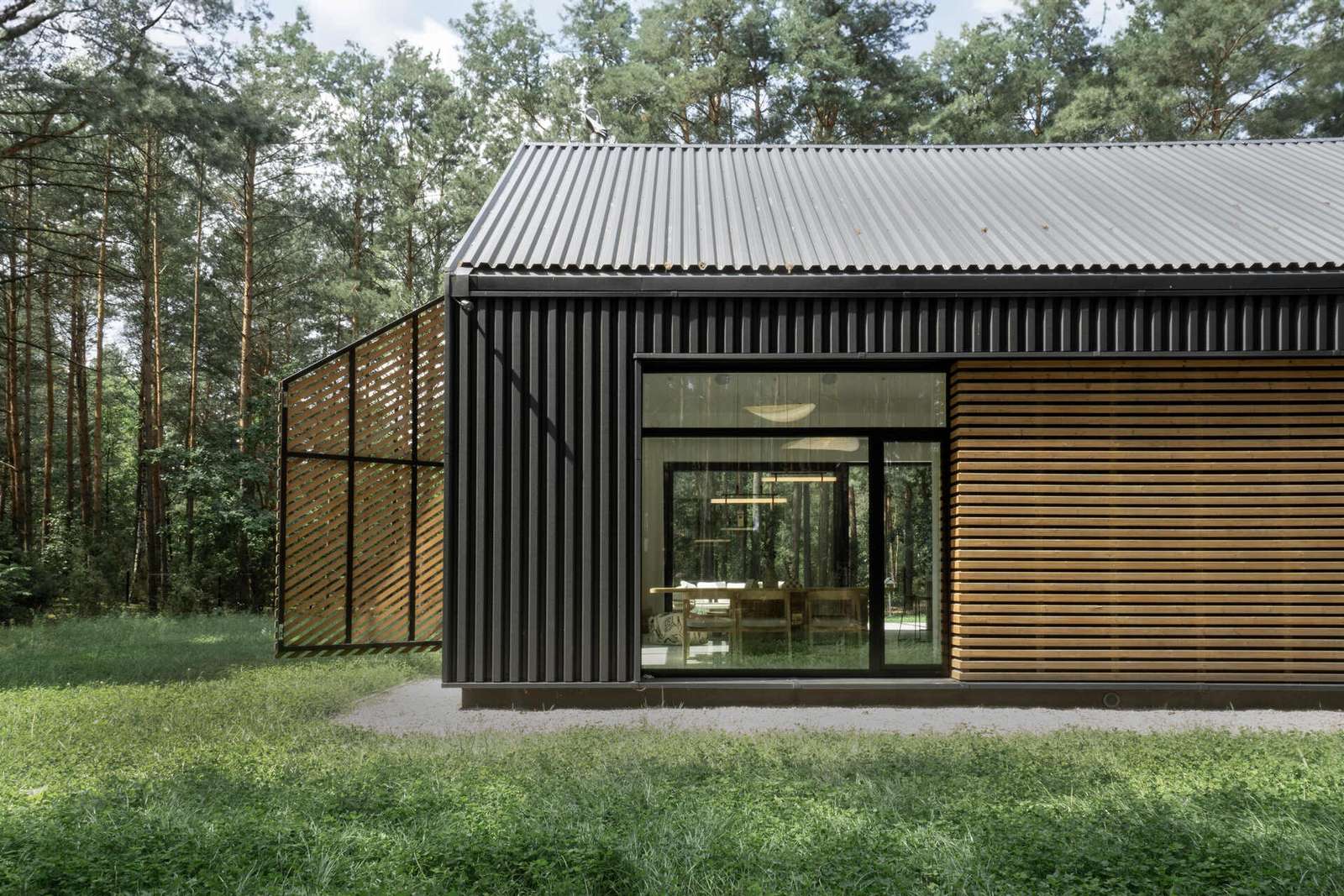 The facade of this modern home is clad in black metal, creating a striking and contemporary appearance, while wood accents add warmth and a natural touch to the exterior.