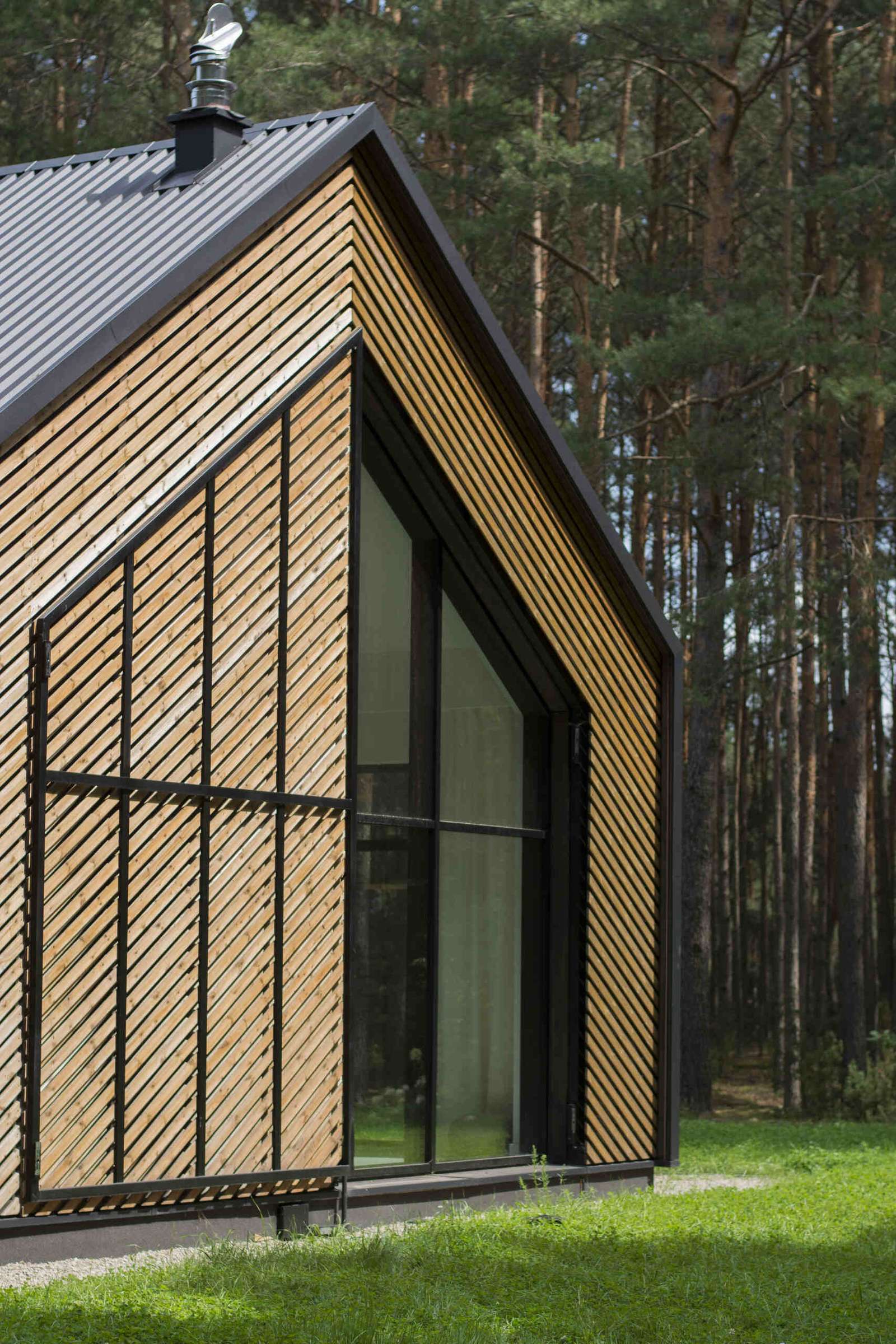 The facade of this modern home is clad in black metal and wood accents like an oversize operational screen.