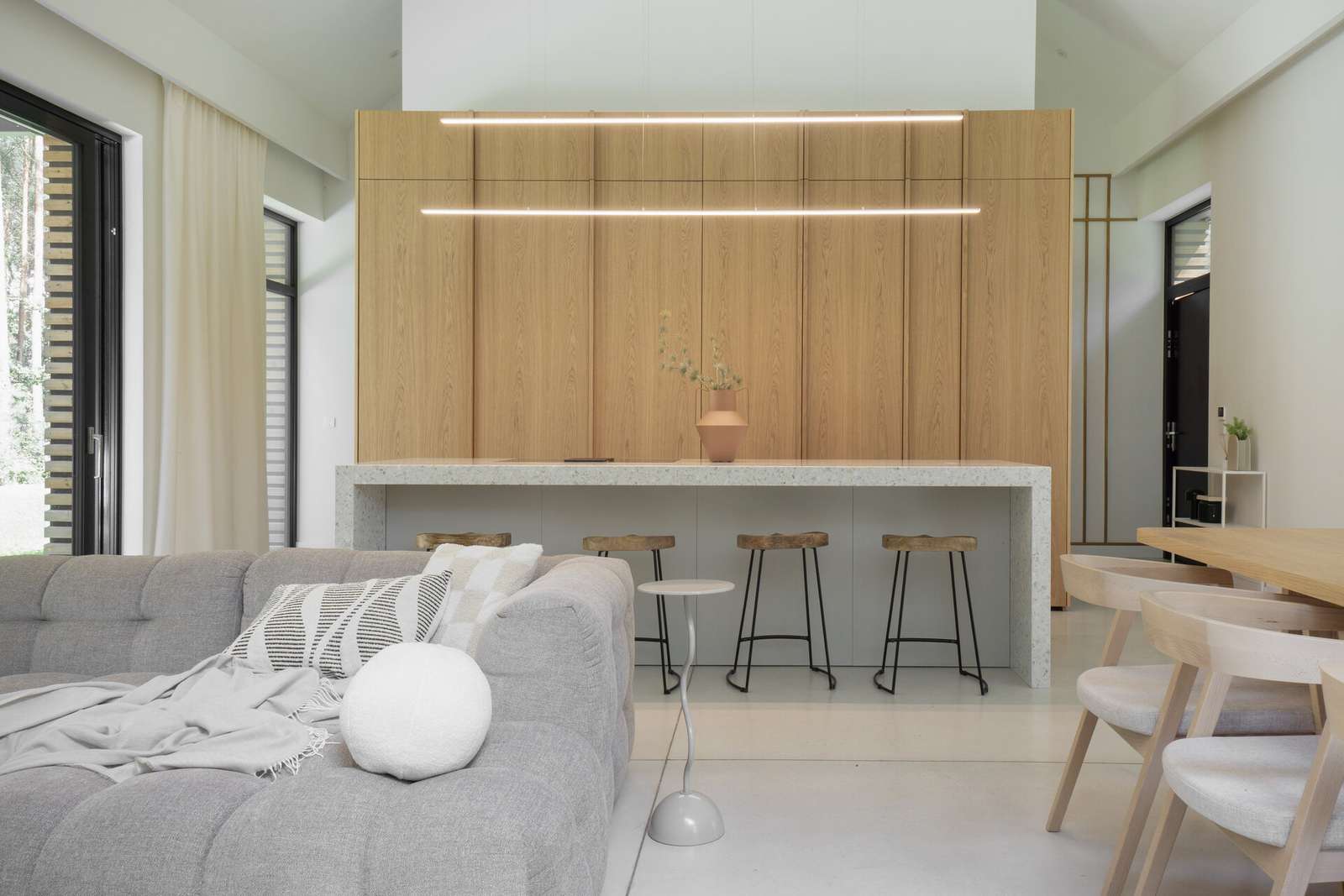In this modern kitchen, the island stands out as a centerpiece, crafted from terrazzo, which adds a unique texture and visual interest, while the wood cabinetry hides the sink and the fridge.