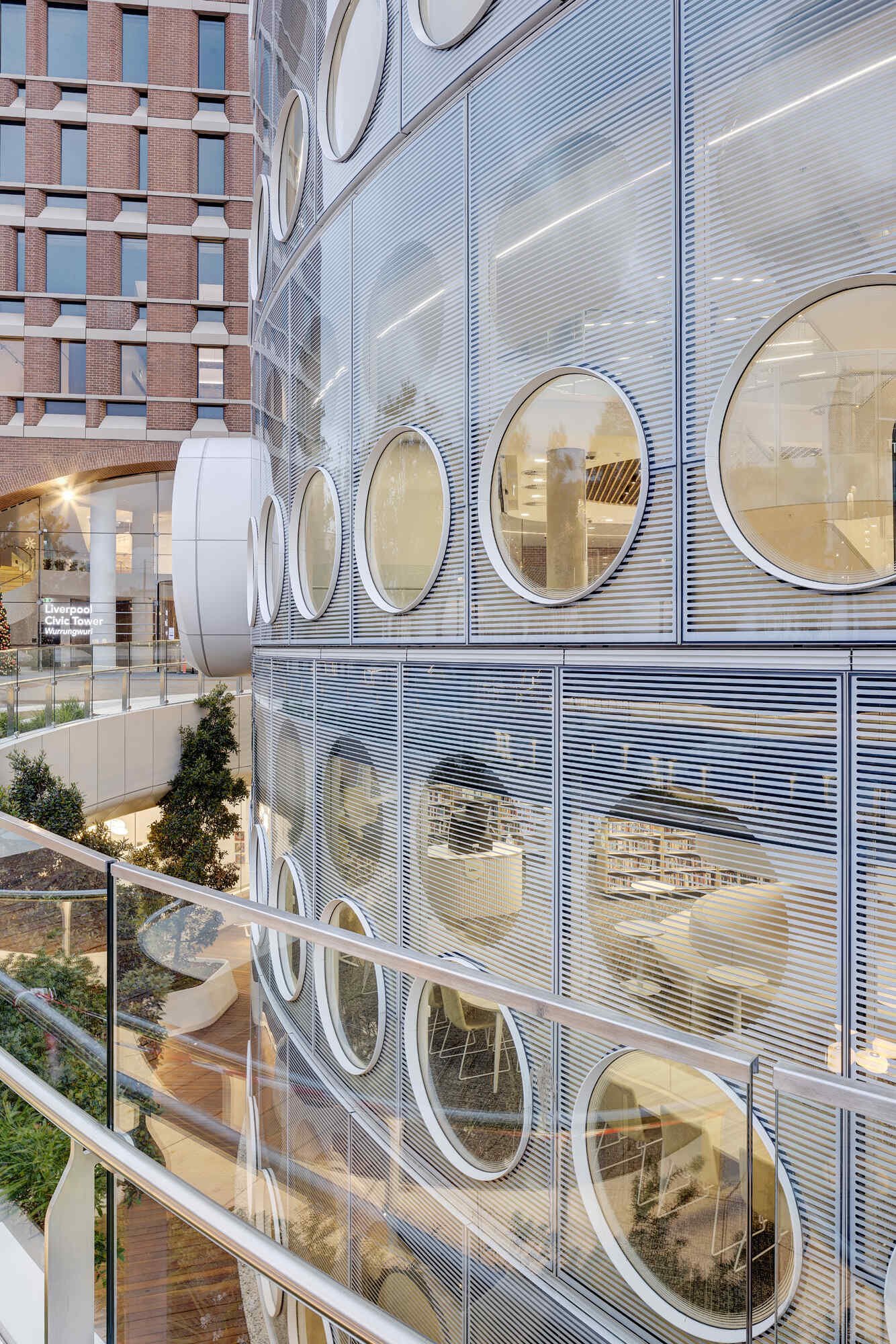 A modern library with a round design, whose exterior facade is covered in matching round windows.