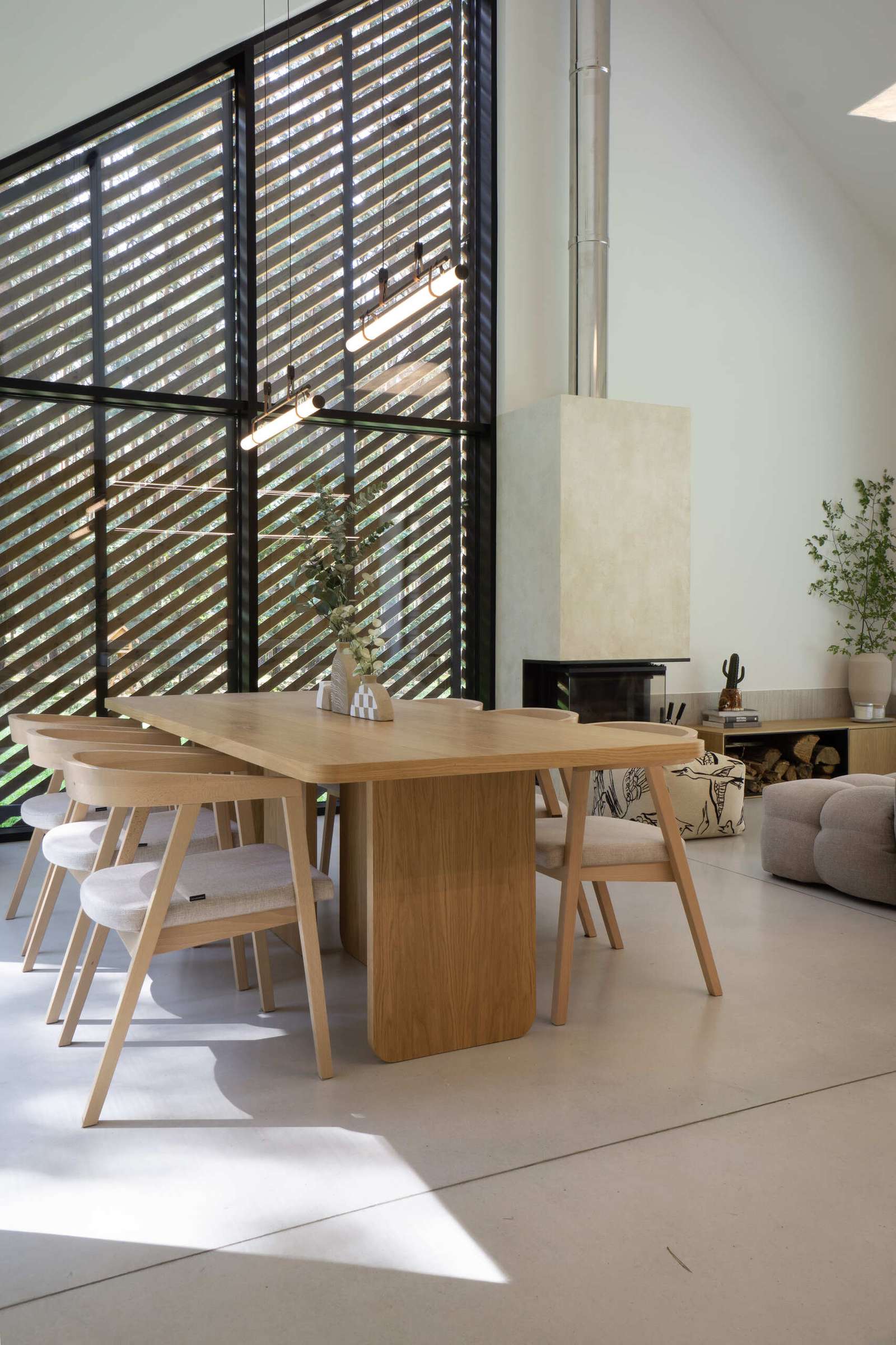 Throughout this modern home, like in the dining area, natural materials such as wood and concrete have been used extensively, adding a sense of warmth and grounding to the sleek design.