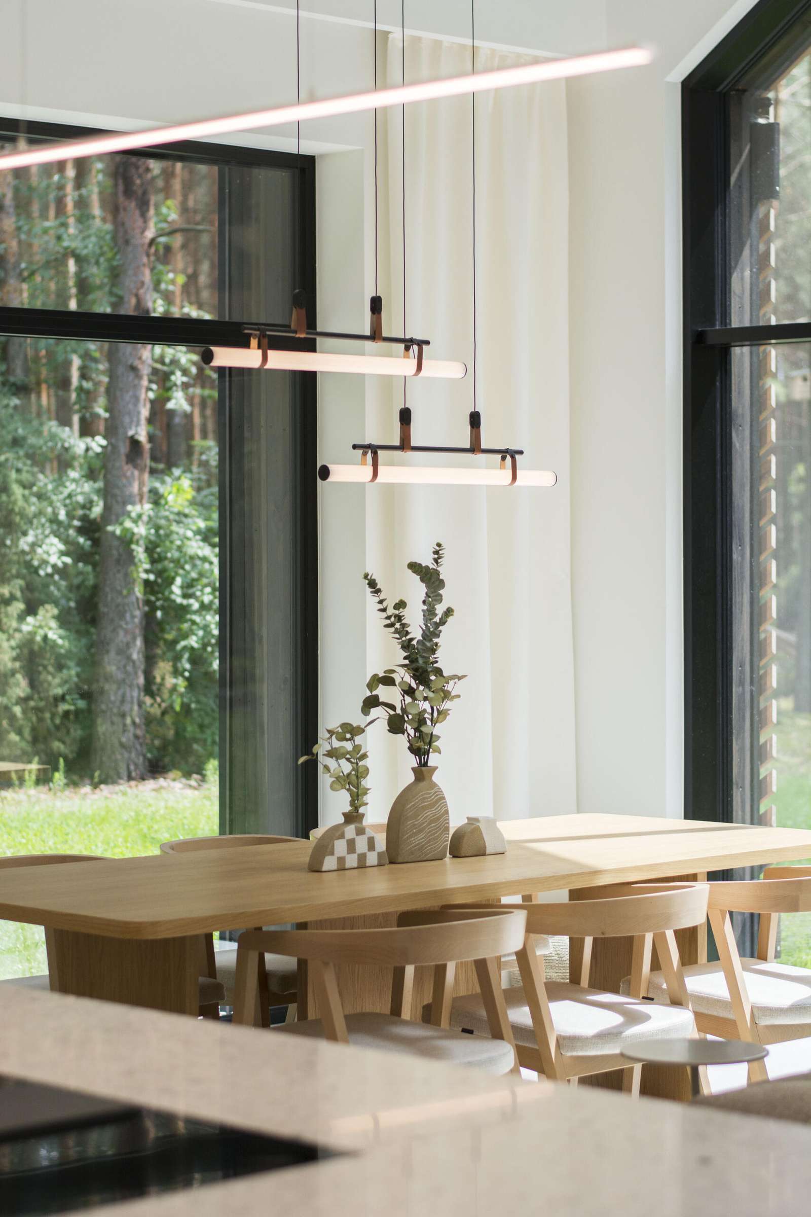 Throughout this modern home, like in the dining area, natural materials such as wood and concrete have been used extensively, adding a sense of warmth and grounding to the sleek design.