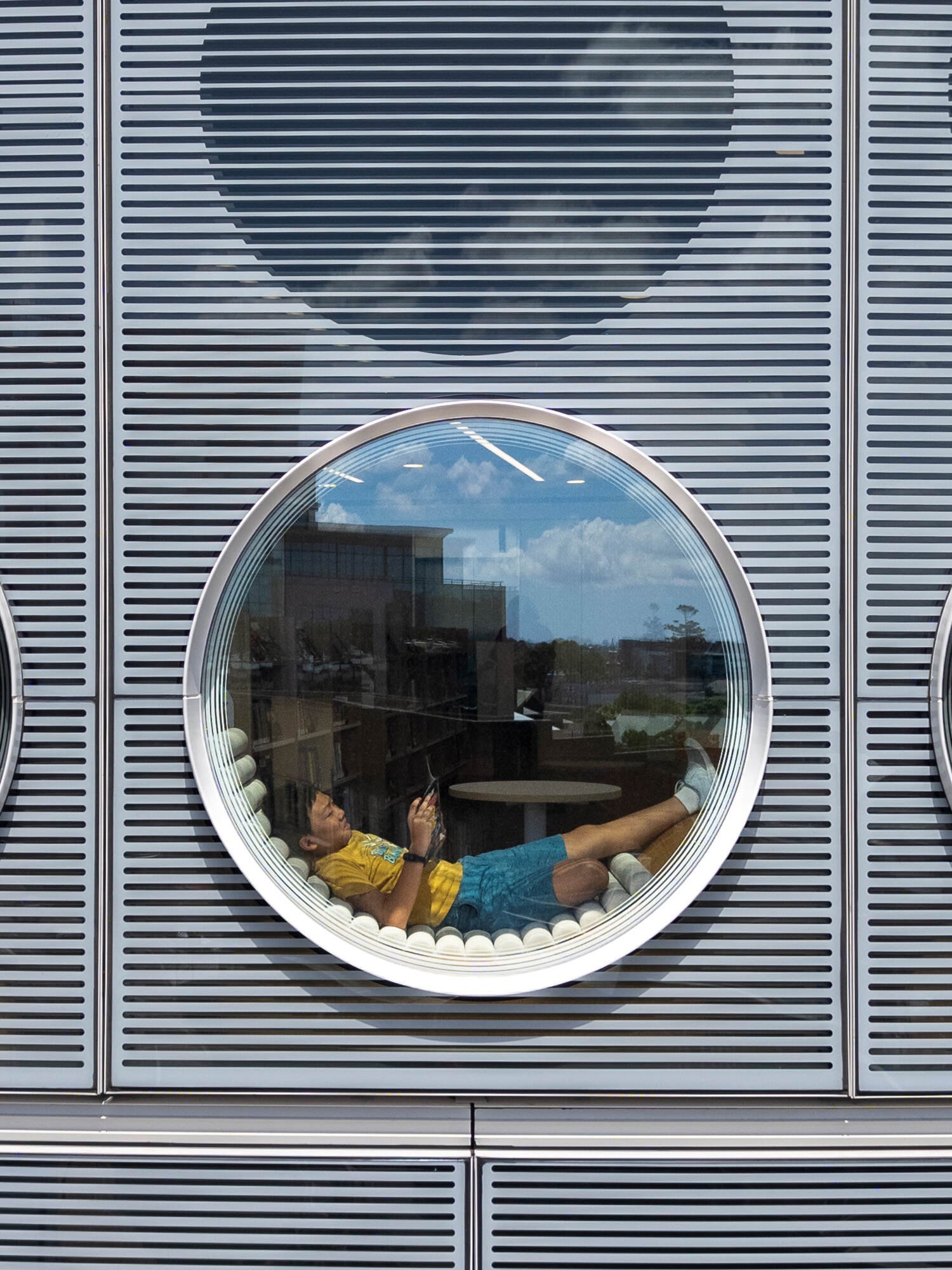 A modern library with a round design, whose exterior facade is covered in matching round windows.