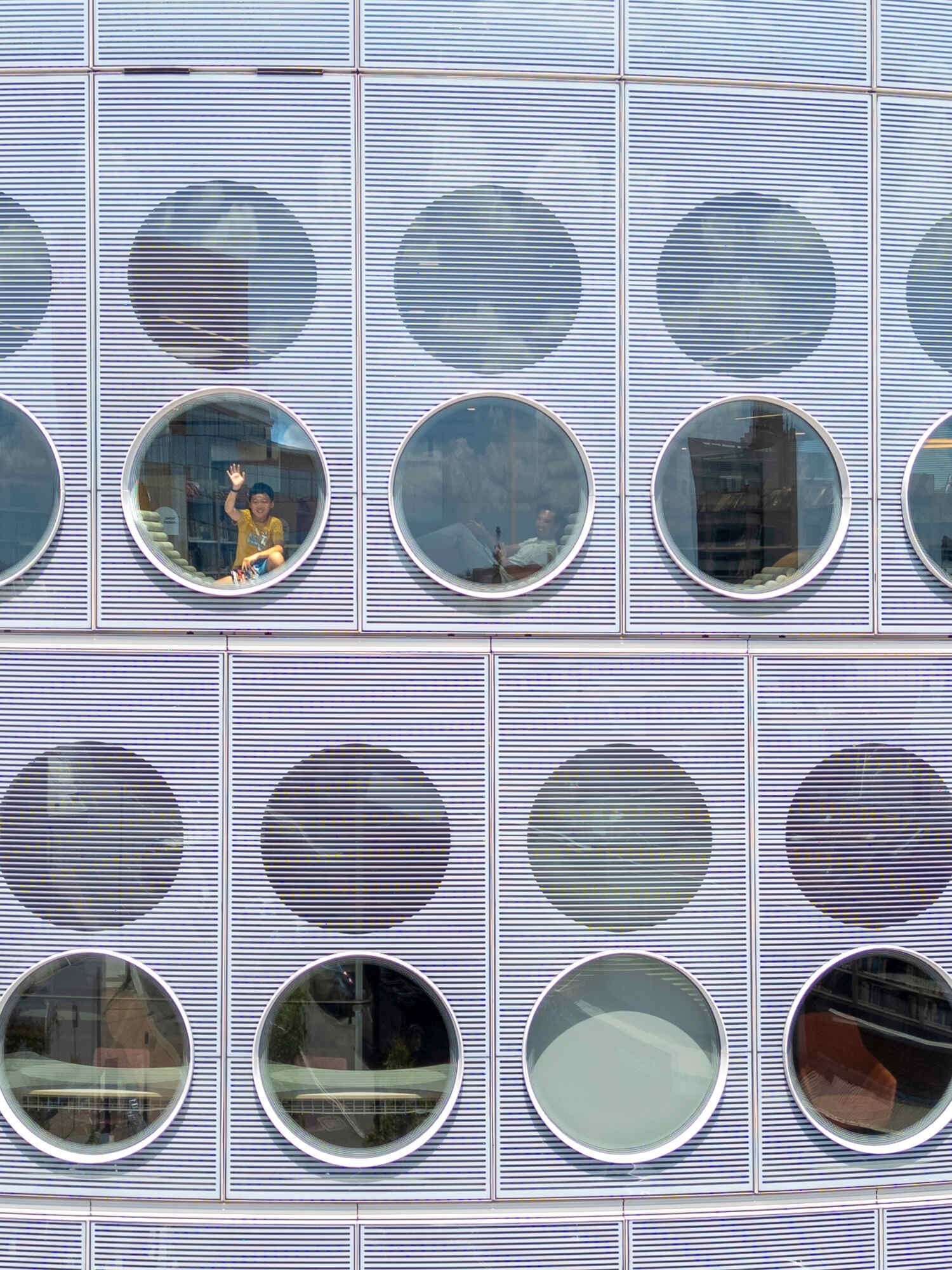 A modern library with a round design, whose exterior facade is covered in matching round windows.