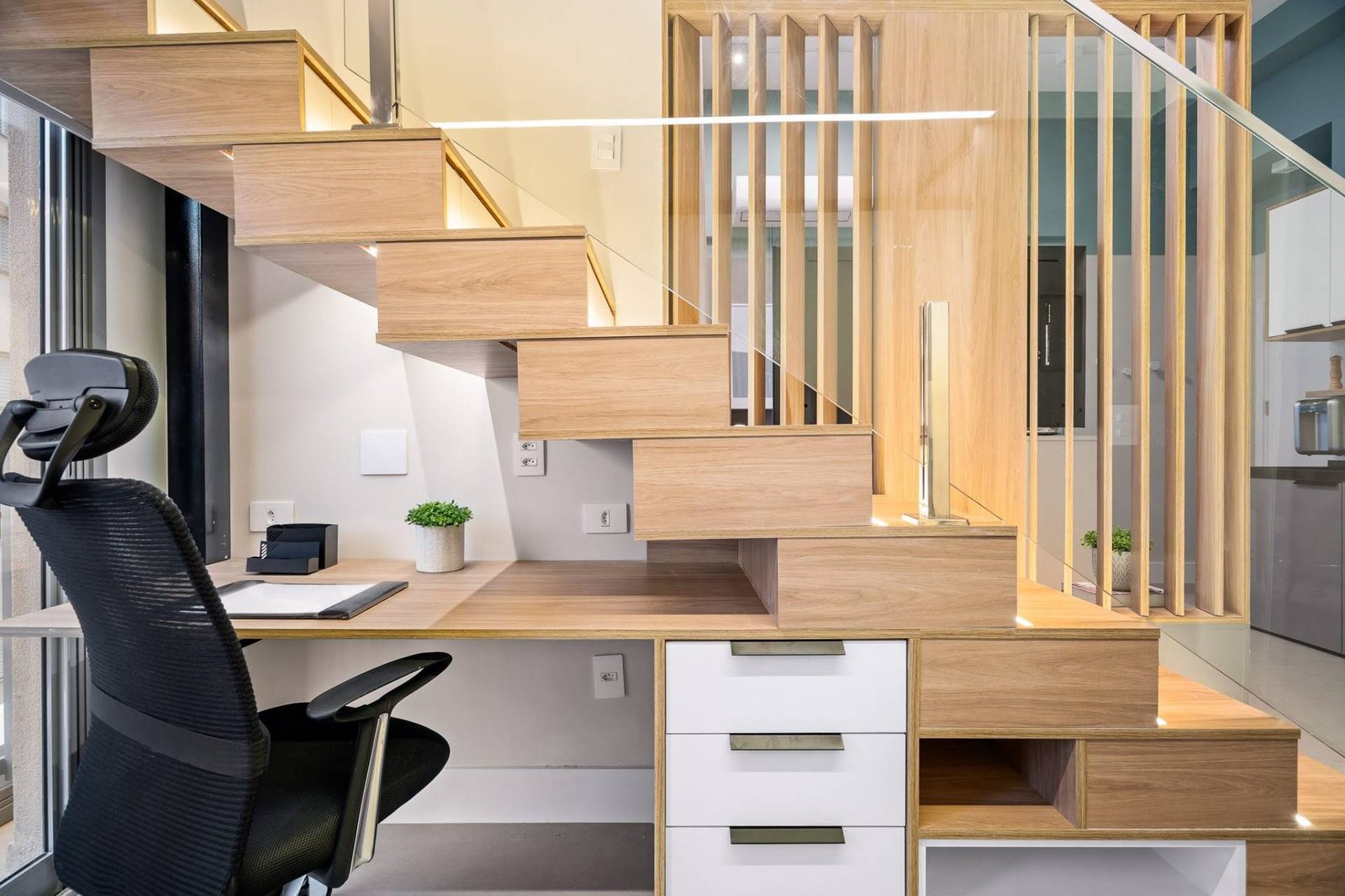 This home office is cleverly integrated beneath the staircase, making full use of an often-overlooked space, with the desk and storage areas fitting seamlessly into the custom carpentry and serves as a functional workspace without interrupting the apartment’s flow.